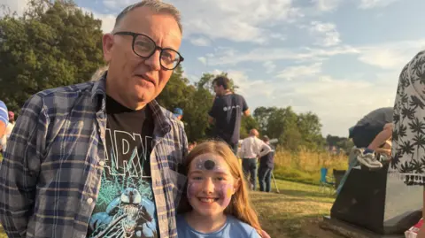 A man with grey hair and glasses and a girl with light hair