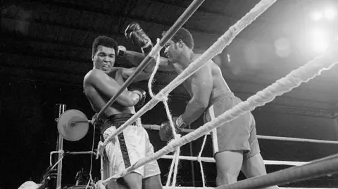 Bettmann through Getty Images George Foreman hitting Muhammad Ali in his famous Rumble in the Jungle Fight in 1974