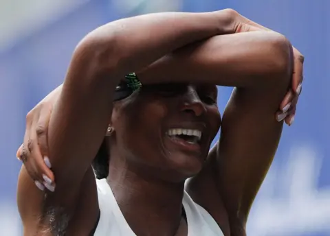 Reuters Hellen Obiri holds her arms over her head and smiles.