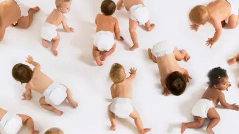 Getty A group of babies wearing nappies crawling all over the floor in a white studio setting