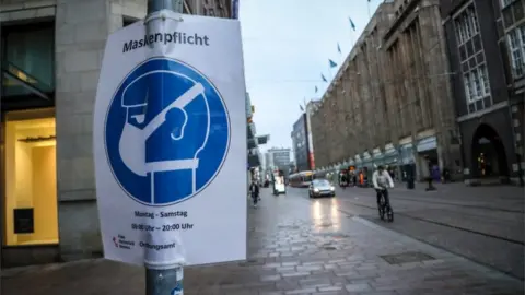 EPA A sign indicating that face masks are mandatory hangs from a pole in the city centre of Bremen, Germany