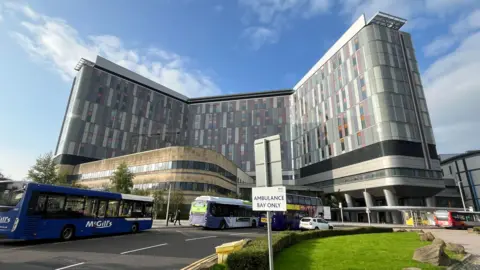 Queen Elizabeth University Hospital pictured from the front entrance, with three buses travelling by