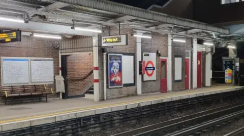 Platform empty shows Tube roundel and departure boards plus railway track