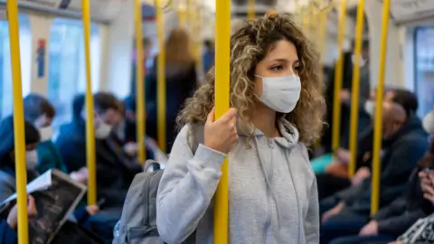 Getty Images Woman on a train in a mask