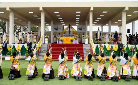 Getty Images People kneeling down in front of a stage during the Mass