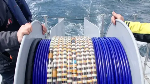 Optics11 A drum holding fibre optic cable, mounted on the bow of a ship.