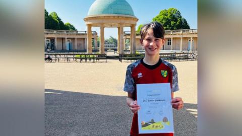 Alfred standing at Eaton Park in Norwich with his certificate