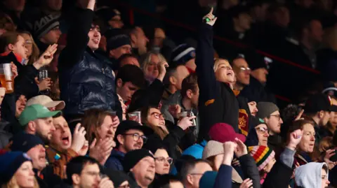 Getty Images A stand full of rugby fans, some of them standing and holding their arms aloft, cheer on the teams as Bristol play Bath at Ashton Gate