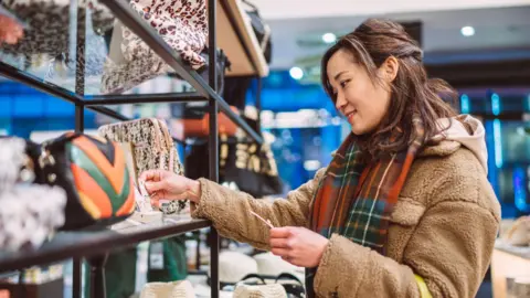 Getty Images Woman looks at price of handbag while shopping in a store