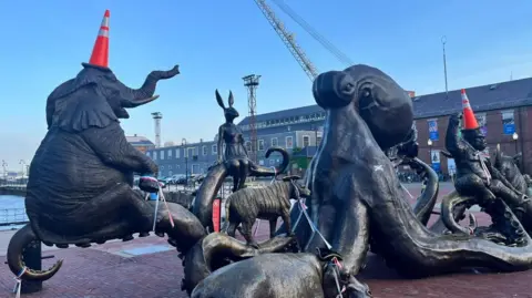 Statues of different animals in Boston with orange traffic cones on their heads.