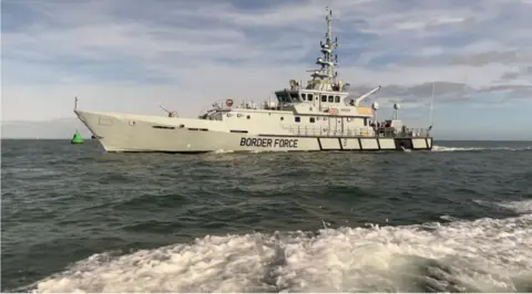 BBC The grey HMC Seeker cutter vessel at sea, with 'BORDER FORCE' along the side and a union flag under the bridge