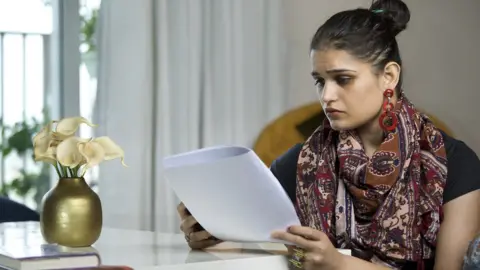 Getty Images A person looking worried whilst looking at a rental contract