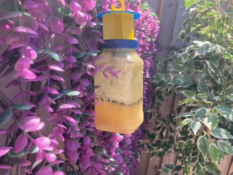 A merky clear through bottle with yellow liquid filled about the third of the way up.