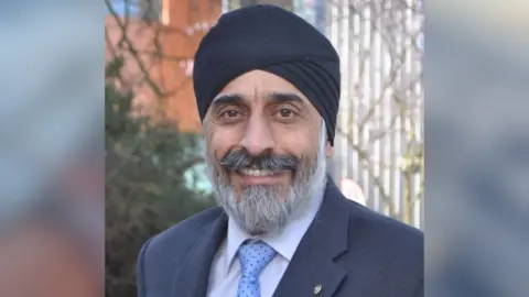 University of York A headshot of University of York Professor Avtar Singh Matharu. He has a grey beard and moustache, and wears a navy suit with a light blue spotted tie and a black turban. 