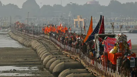 Getty Images Hindu holy men or Sadhus walk in a religious procession of Atal Akhara across a floating pontoon bridge, ahead of the Maha Kumbh Mela festival in Prayagraj on January 1, 2025. (Photo by Niharika KULKARNI / AFP) (Photo by NIHARIKA KULKARNI/AFP via Getty Images)