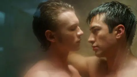 Connor Storrie and Hudson Williams seen in a still from Heated Rivalry facing each other, head and shoulders, in a steamy shower scene