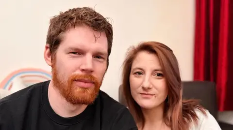 Head and shoulders photo of a man and woman looking directly into a camera