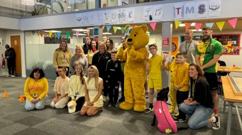 Pudsey bear with a group of adults and children at Taylored Mentoring in Gloucestershire.