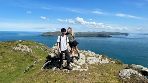 Lois Roberts Lois and Aaron standing side by side on a hilltop overlooking the sea