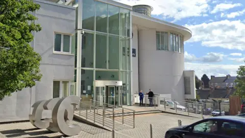 A light-coloured court building with a large floor to ceiling glass entrance way.