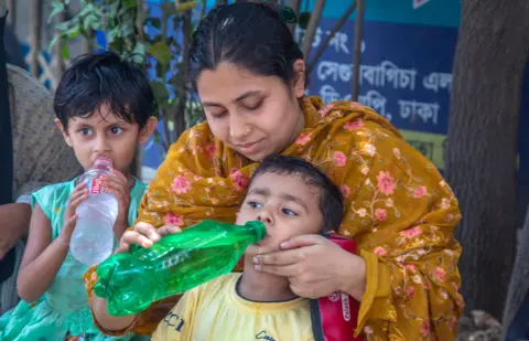 Children drink from water bottles during the heatwave in Dhaka, Bangladesh, 22 April 2024.