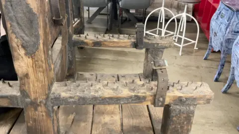 The arms of the chair with metal spikes on them