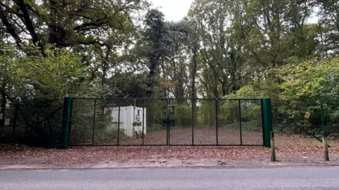 Julia Gregory/BBC A high gate and bollards in front of the oil drilling site