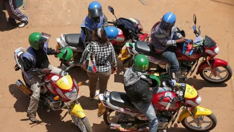 Getty Images A woman in Rwanda surrounded by motorbike riders