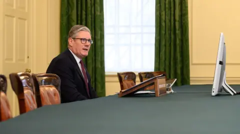 PA Media Sir Keir Starmer sits in an otherwise empty cabinet meeting room talking to a computer screen.