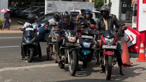 About six motorcyclists lining up at a petrol station in Sri Lanka 