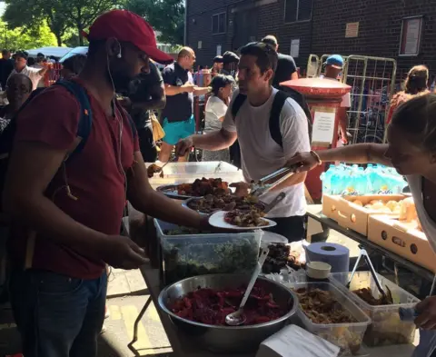 Volunteers serve food to people near Grenfell Tower