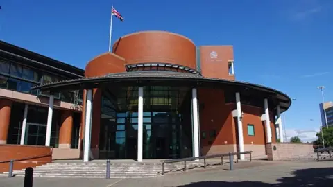 A brown brick court house with a large glass entrance door