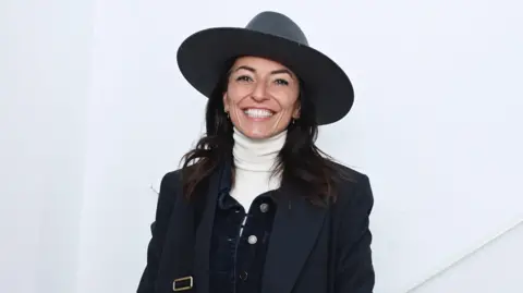 Davina McCall wearing a big hat and smiling.