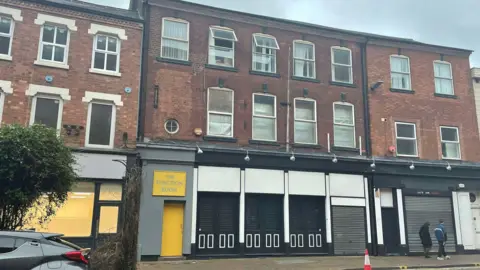 Three-storey brick building bordered by similar properties