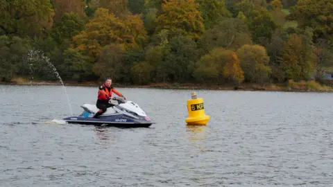 Loch Lomond & The Trossachs National Park Authority A man on a white and blue jet ski, riding it near a buoy 
