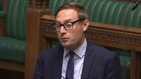 Parliament TV Olly Glover, the Liberal Democrat MP for Didcot & Wantage, speaking in parliament. He is pictured against the green benches and is wearing 