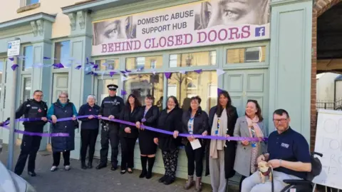 Lancashire Police Police officers and other people involved standing behind a purple ribbon in front of the Behind Closed Doors centre in Fleetwood