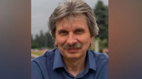 Sergei Krajev, who has a moustache, wearing a blue shirt and looking into the camera