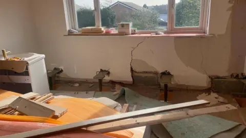 Simon Thake A bedroom with stripped back plasterboards and wooden planks lying across the floor