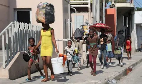 Reuters People walk towards a shelter with their belongings fleeing from violence around their homes, in Port-au-Prince, Haiti March 9, 2024