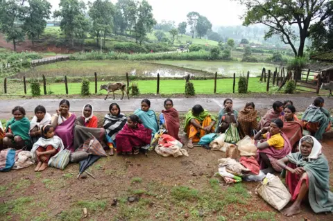 WaterAid/Ronny Sen Baiga women queue outside the local ration shop.