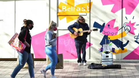 Pacemaker A busker performs as shoppers walk by in Belfast