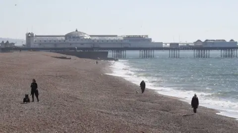 PA Media People walk along Brighton beach on Sunday 5 April