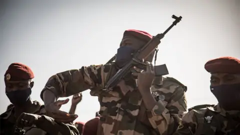 A soldier straps on his weapon during the state funeral of Mali's recently deceased ousted President Ibrahim Boubacar Keita, in Bamako, on January 21, 2022.