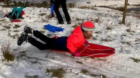 People tobogganing near Capel Curig, in Eryri, also known as Snowdonia