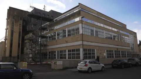 Avon and Somerset Police Image of the Plymouth House base in Bath. It is a beige coloured building with lots of windows and a metal staircase on the outside. Cars can be seen parked alongside the pavement