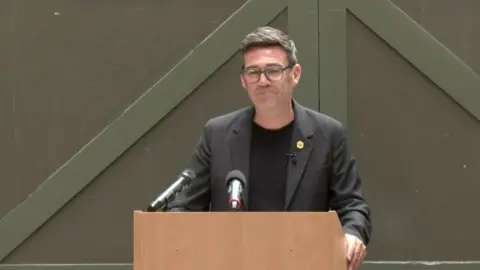 Burnham smiling in front of a lectern during his speech