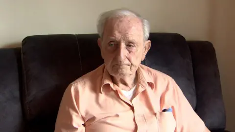 91-year-old resident Eamon Melaugh sitting in an armchair as he speaks to BBC News NI