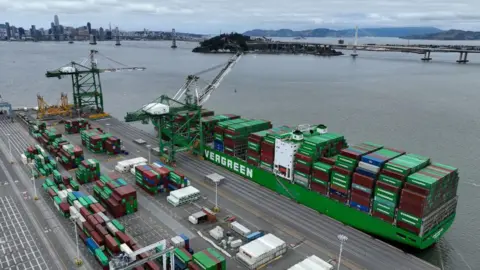 A green container ship loaded with containers sits docked at the Port of Oakland by two cranes on June 07, 2023 in Oakland, California. 