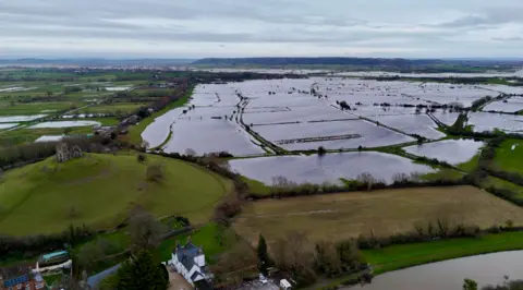 A drone shot showing flooded fields on the Somerset lewvels with a small village in the foreground